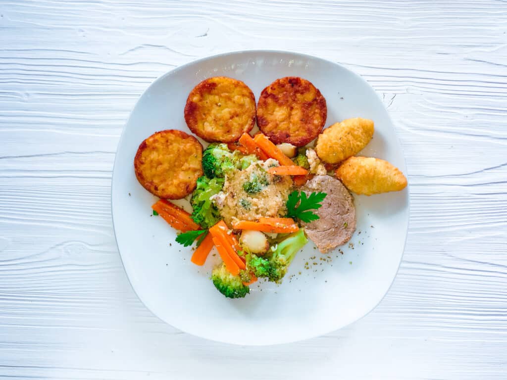Überbackene Schweinemedaillons mit Kroketten und Gemüse