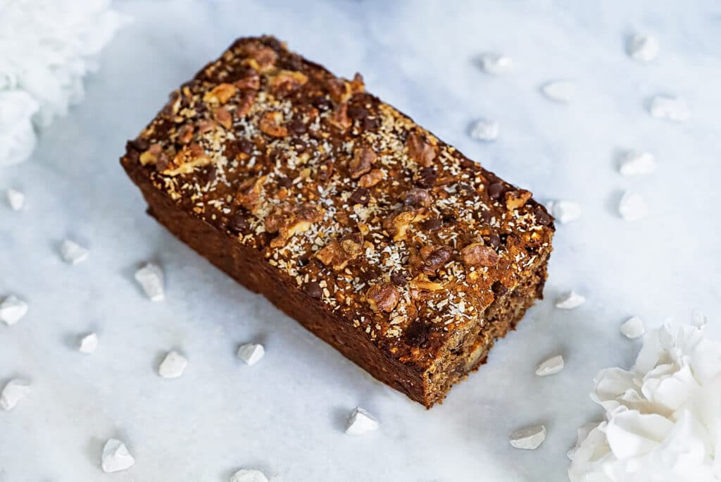 Gluten-, zucker- und milchfreier Bananenkuchen mit Schokodrops auf einer Marmorplatte serviert. 