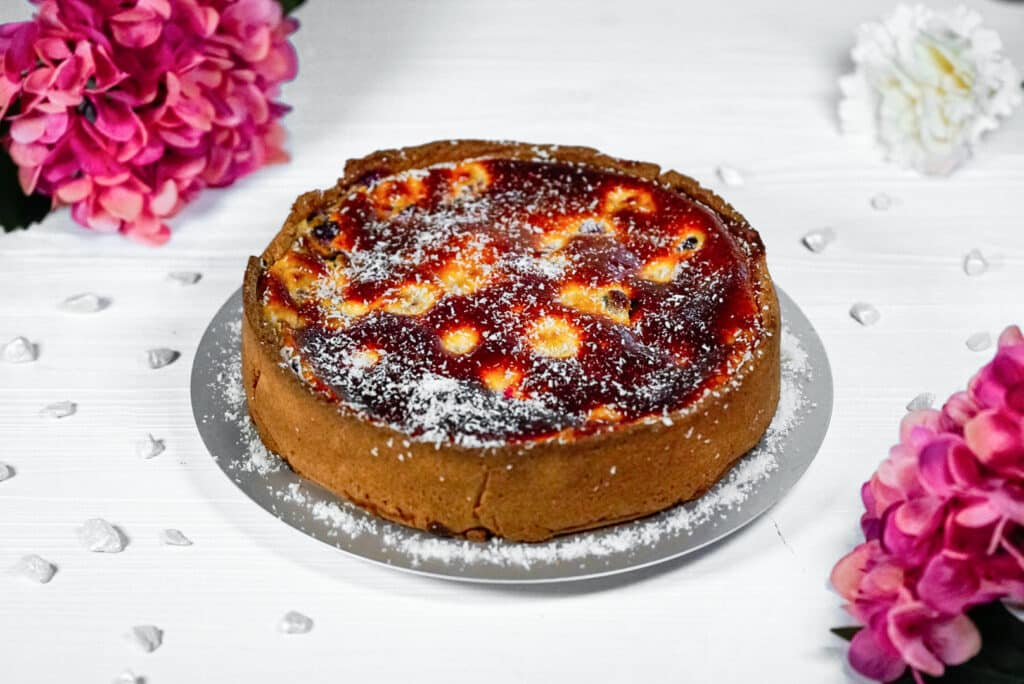 Gebackener Cheesecake mit Beeren auf einem weißen Tisch serviert. 