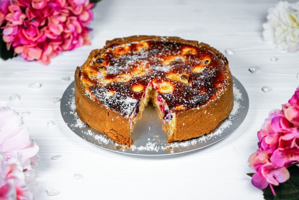 Gebackener Cheesecake mit Beeren auf einem weißen Tisch serviert. 