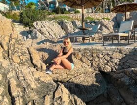 Sportlerin-auf-einem-Felsen-am-Meer-sitzend