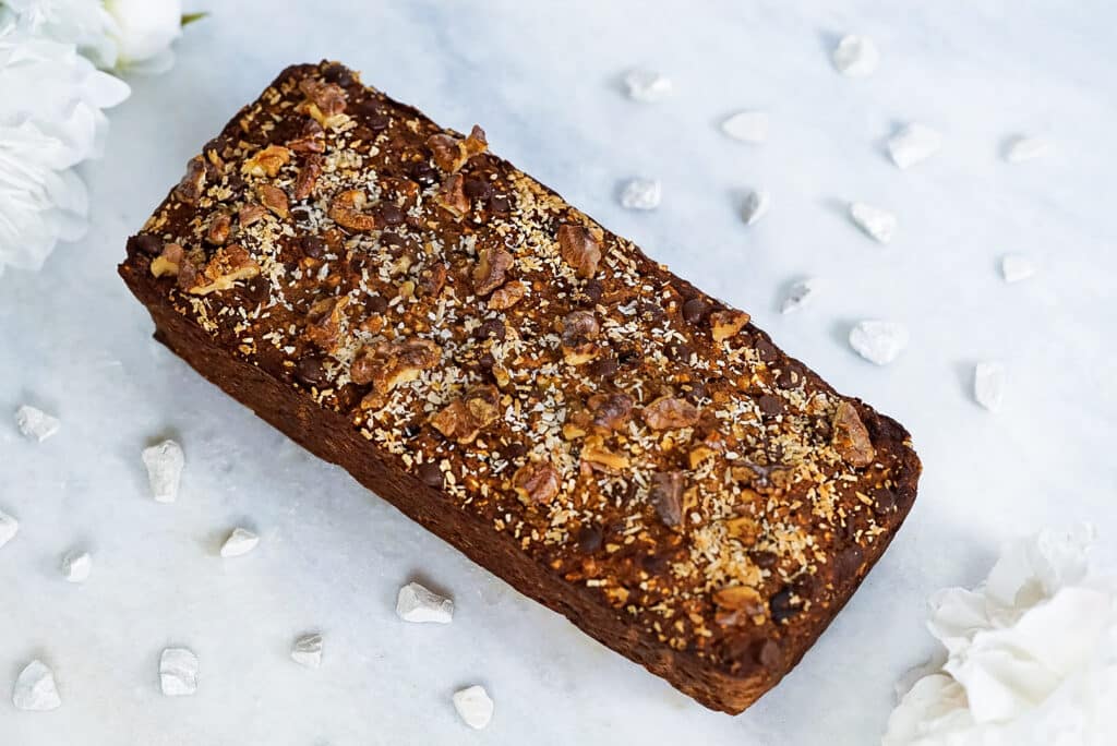 Gluten-, zucker- und milchfreier Bananenkuchen mit Schokodrops auf einer Marmorplatte serviert. 