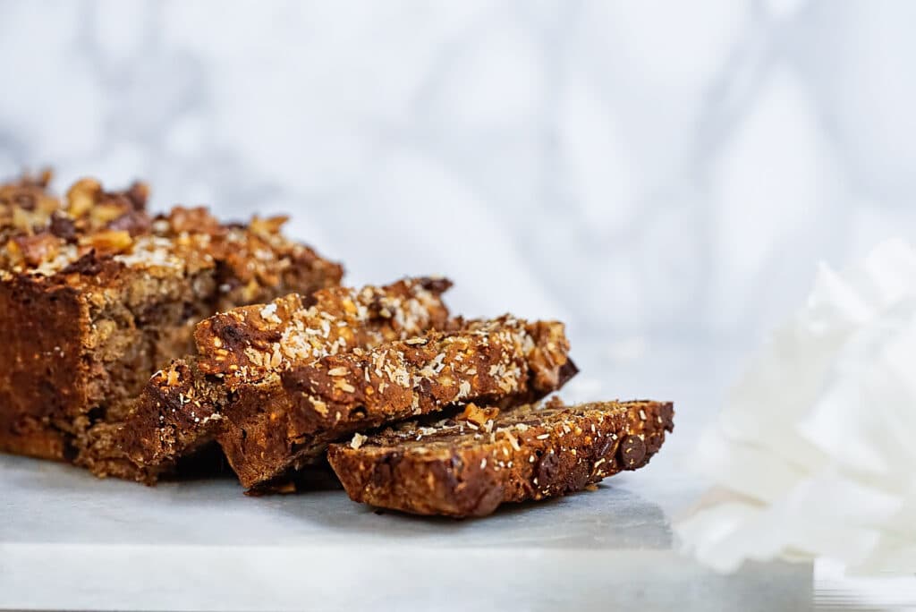 Gluten-, zucker- und milchfreier Bananenkuchen mit Schokodrops auf einer Marmorplatte serviert und in Scheiben geschnitten. 