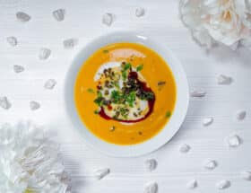 Kürbiscremesuppe garniert mit Kokosmilch, Kürbiskernen, Kürbiskernöl und frischer Petersilie.